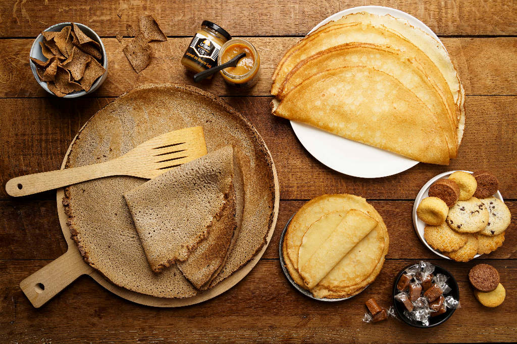 Gamme complète de la Crêperie Le Guen : galettes, crêpes, biscuits bretons et caramels présentés sur une table en bois